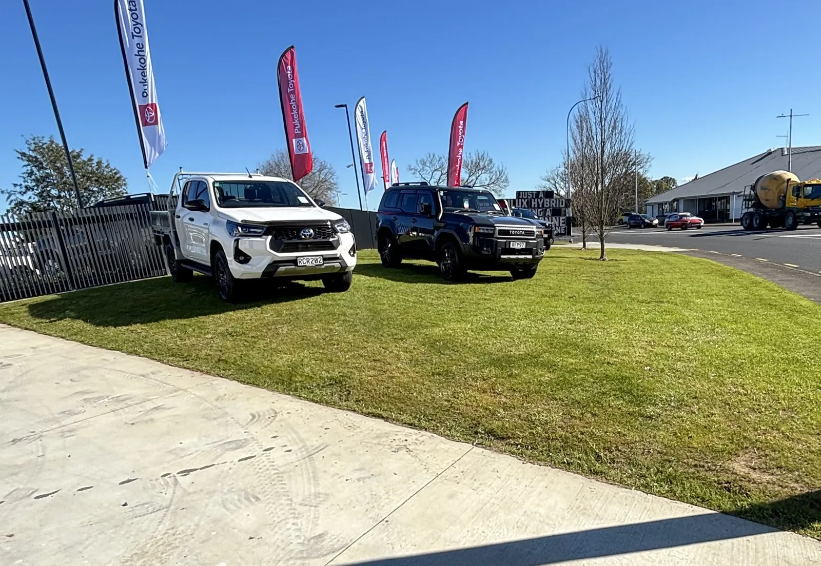 A mown grass frontage sweeping along a dealership forecourt to the road